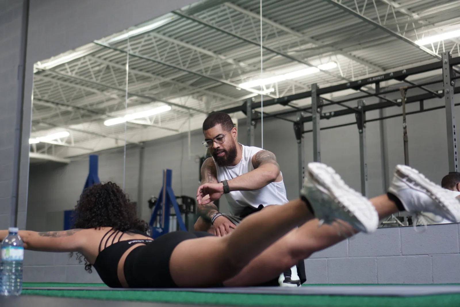 Coach guiding a client through core training on the turf