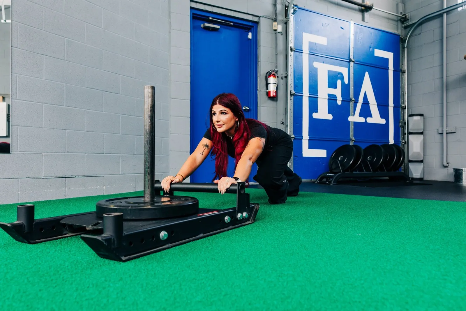 Lisa Hinson pushing a training sled on the Forever Aesthetic turf
